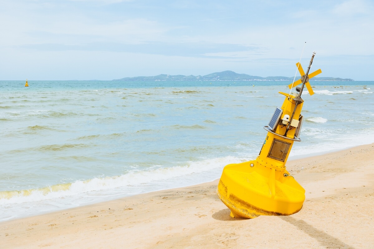 故障のため砂浜で修理を待っている、CCTVカメラ付きの黄色い海洋ブイ環境センサー。